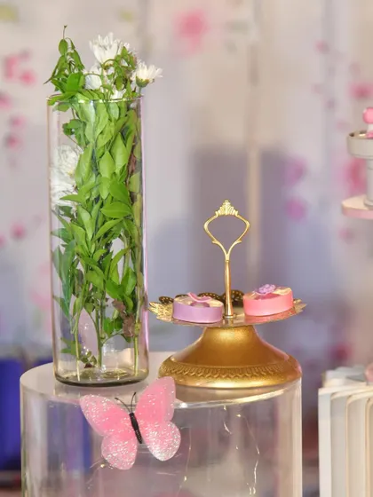 Even the smallest details, like these miniature cakes on a decorative stand and a glittery pink butterfly, contribute to the overall magic of a themed party.