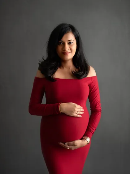 A bold and beautiful choice. This mom-to-be looks absolutely stunning in a classic, off-the-shoulder red gown against a simple grey backdrop.