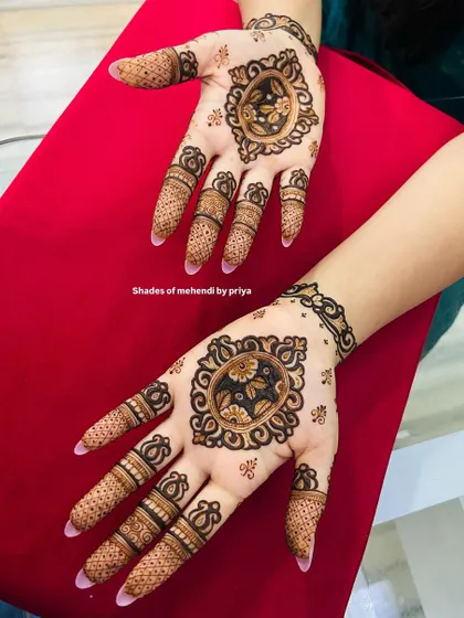 A different style of engagement mehendi, with a focus on bold floral medallions on the front and back of the hands.