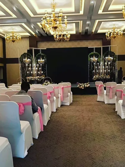 An indoor event space ready for a reception, with elegant chandeliers and neatly arranged guest seating.