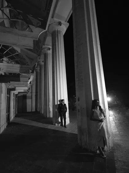 An architectural black and white portrait, using the grand columns to frame the couple and create a sense of scale and drama.