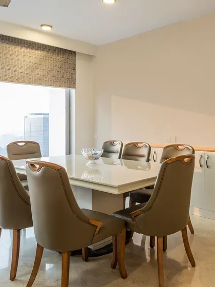 A spacious and elegant dining room with a large white-top table and comfortable leather-finish chairs, perfect for hosting dinner parties.