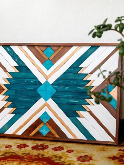 Our geometric blue wood art displayed on the floor, surrounded by plants. This highlights its versatility and how well it pairs with bohemian and natural decor elements.