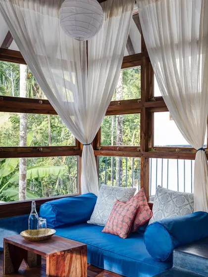 The cozy seating nook in the Sky Room at Jalakara, a perfect spot for reading while being surrounded by treetop views.