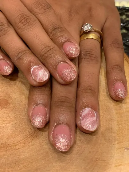 The perfect nails for a bride-to-be. This elegant set combines a soft pink glitter ombre with a beautiful white marble accent nail for a sophisticated bridal look.