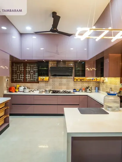 A wide view of a luxurious mauve kitchen in a 6BHK independent villa. The high-gloss finish and modern pendant light create a glamorous and inviting space, perfect for a large family.