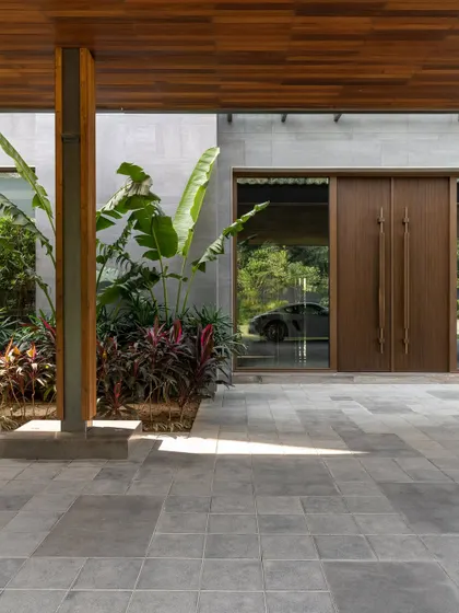 The entrance of the K Residence, where a glass facade offers a glimpse of a luxury car, reflecting the client's passions. The design thoughtfully integrates personal elements into the architectural narrative.