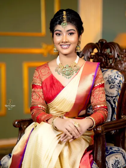 Amrutha Prem looking regal in a cream and red Kanjivaram saree, paired with a red brocade blouse with puff sleeves.