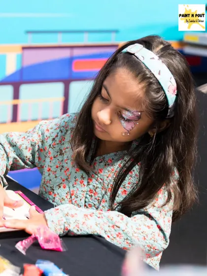 A young girl with a pretty butterfly glitter design around her eye, showing that sparkle is for all ages.