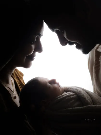 A beautiful rim-lit portrait of a family admiring their newborn. This black and white photograph has a timeless, classic feel that emphasizes emotion and connection.