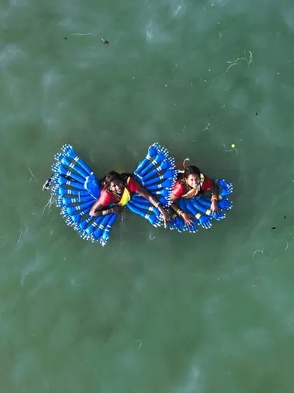 This top-down drone photo captures two performers during the Kulasai Dasara festival in Tamil Nadu. The vibrant blue costumes create a stunning butterfly-like shape on the surface of the water, showcasing the festival's unique and colorful traditions.