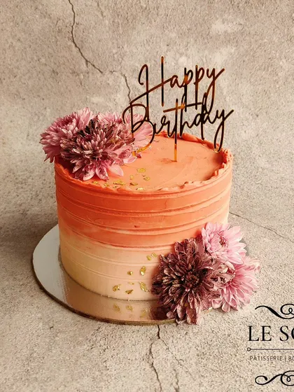 Pinks on the outside and pinks on the inside. This half-kg Chocolate Raspberry cake features a beautiful coral pink ombre buttercream finish and is decorated with fresh flowers.