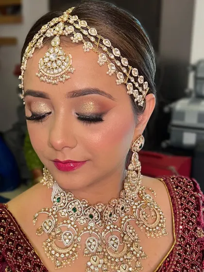 A close up on the eye makeup, featuring a brilliant gold glitter lid and a soft crease color, paired with a vibrant pink lip.