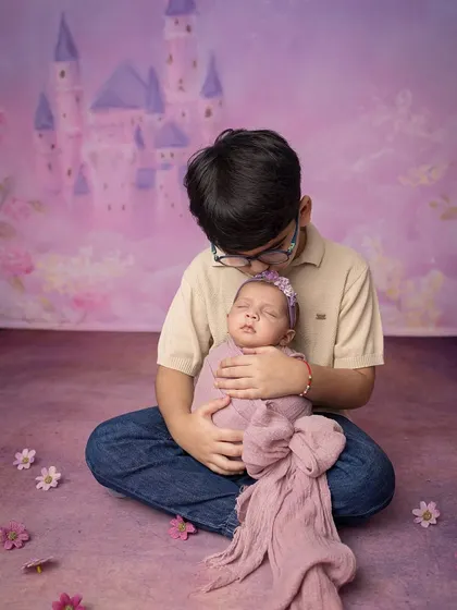 A gentle moment between siblings. The older brother looks down lovingly at his sleeping sister, a story of new responsibility and love.
