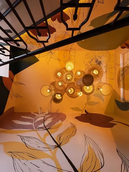 A top-down view of the staircase, showing how the mural and lighting design extend across the ceiling, enveloping the entire space in art.