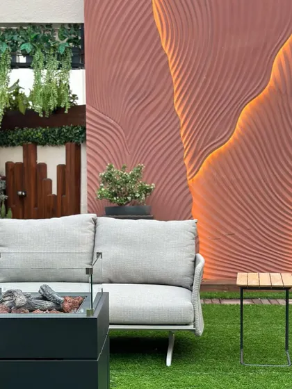 A close-up of the terrace seating area, featuring a modern sofa next to a firepit and a sculptural, illuminated wall. This composition shows our attention to detail in creating functional art within a landscape.