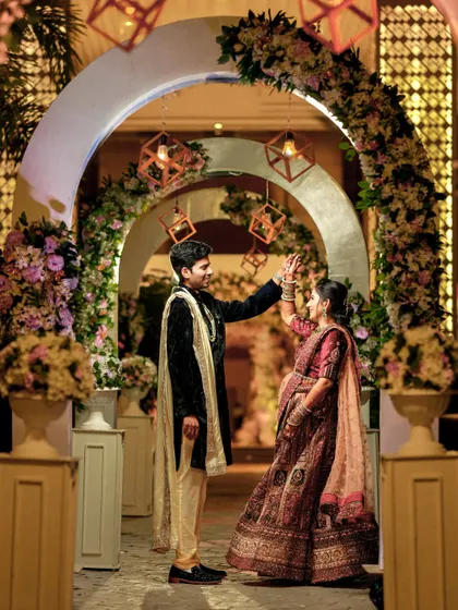 A playful dance move captured under the floral arch, showing the couple's joyful celebration.