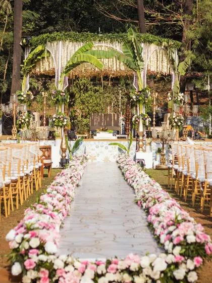 A classic South Indian wedding mandap featuring grand arches made of banana leaves, a ceiling of tuberose garlands, and a beautifully decorated aisle for the bride's entrance.