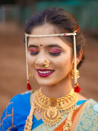 A close-up shot to appreciate the artistry of the bridal look. This photo highlights the detailed makeup, the traditional bindi, and the intricate design of her gold necklace and mundavalya. It’s a celebration of bridal beauty.