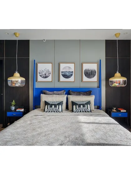 In the son's bedroom, a four-poster bed in a vibrant blue is the centerpiece. This is balanced with a neutral gray wall, monochrome art, and unique pendant lights, creating a youthful yet stylish retreat.