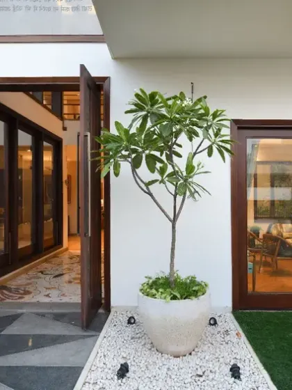 Near the entrance of Ashraya Residence, a serene water body serves as a Vaastu-compliant feature. The entrance corridor floor is adorned with an intricate mosaic pattern, setting a warm and inviting tone.
