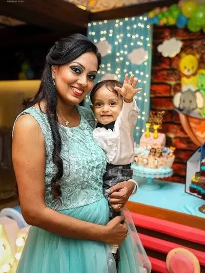 A mother holds her son as he gives a happy wave to the camera.