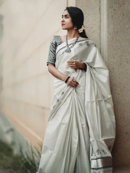 A minimalist and elegant portrait in a classic white and black Kerala saree. The clean lines and soft, natural light create a serene and sophisticated look.