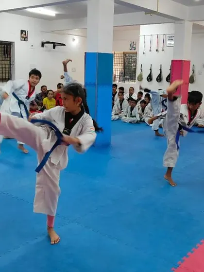 An instructor demonstrates a high kick to the class.