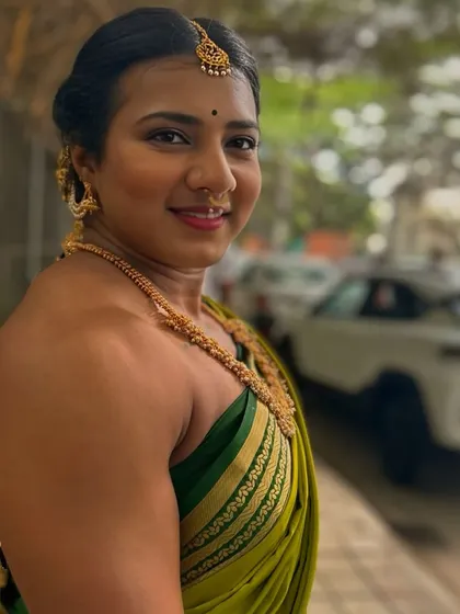 A side profile in a green saree, showing a softer smile that contrasts with the powerful shoulder and arm definition. It’s about breaking trends and embracing tradition with confidence.