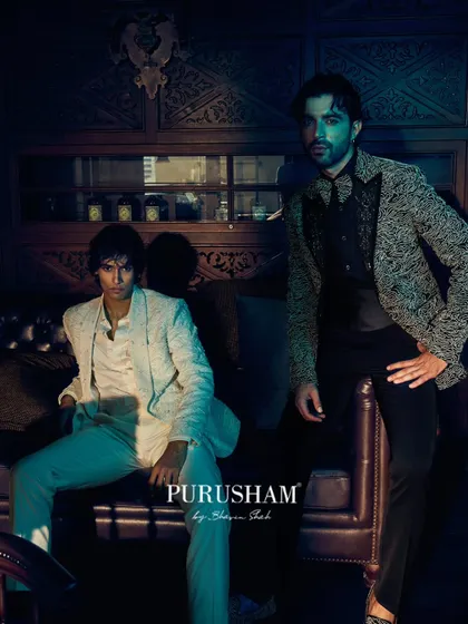 Shadows dance and luxury lingers. This image captures two distinct looks: a textured white jacket and a black patterned blazer. It shows how embroidered precision meets midnight drama, commanding attention with every glance.