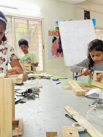 The workshop is buzzing with activity as these young carpenters work on their wooden crates. Each child gets to practice measuring, nailing, and assembling.