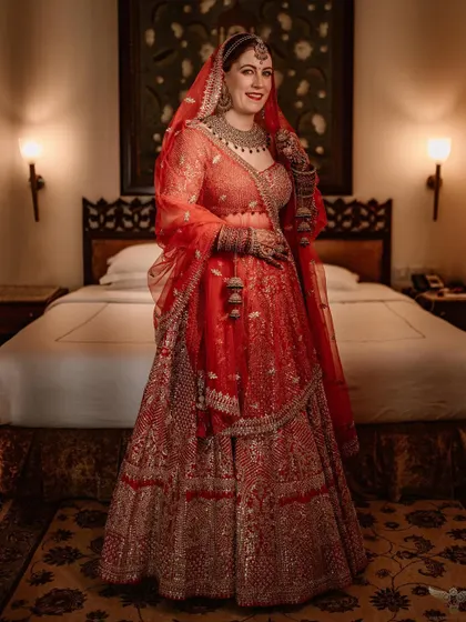 A classic, full-length bridal portrait taken in a hotel room. The elegant decor and her regal pose give this shot a timeless and sophisticated quality.