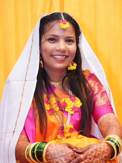 The bride during a Haldi ritual, with a white cloth over her head.