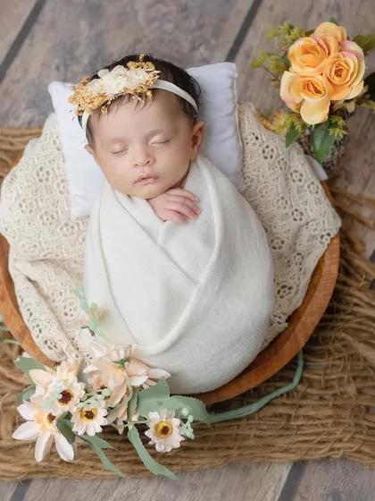 A rustic and gentle setup with a newborn sleeping in a wooden bowl on a jute mat.