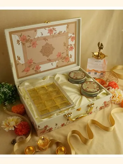 The "White Bliss" hamper unboxed, revealing a tray of sweets and two matching decorative tins, all nestled in satin lining.