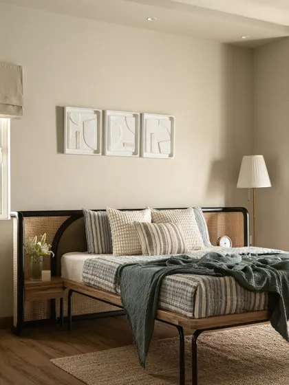 This bedroom marries industrial soul with artisanal heart. The bed frame combines black metal with a cane-webbed headboard, set against abstract canvases that float like captured thoughts.