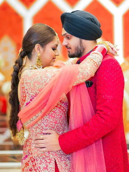 An intimate portrait of the Sikh couple, capturing a moment of quiet connection. The focus is on their embrace and the beautiful details of their traditional outfits.