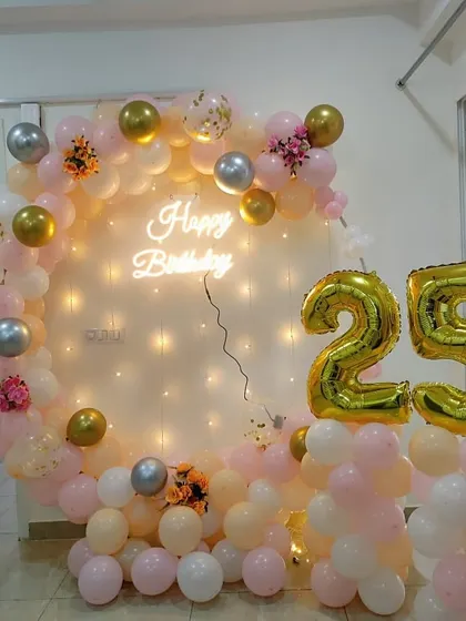 A delicate and pretty 25th birthday balloon ring in pastel pink, peach, and white, with floral accents and light-up numbers.