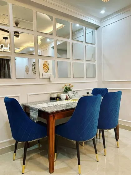 A full view of the dining setup, where the vibrant blue chairs provide a beautiful contrast against the neutral white walls with classic molding.