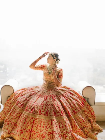 A bride basking in the light, her magnificent lehenga spread around her. This is a classic, elegant bridal portrait that every bride dreams of.