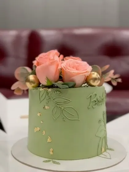 This sage green cake is beautifully complemented by fresh pink roses and delicate gold leaf. The hand-etched floral design on the side adds a subtle, artistic touch, perfect for a bridal shower.