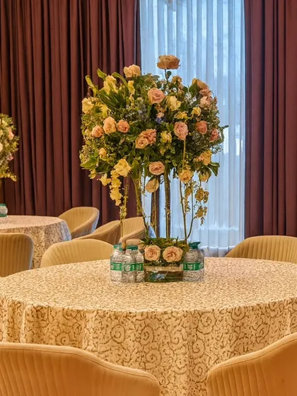 An elegant floral centerpiece on a round table with a patterned tablecloth. This classic setup is perfect for a formal banquet or milestone celebration.