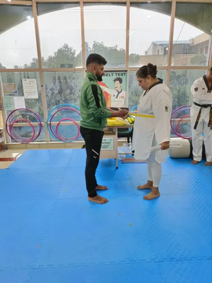 An adult student receives her yellow belt.