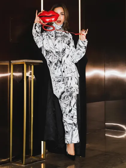 A full-length version of the playful portrait with the lip-shaped phone, showing off the complete look from head to toe.
