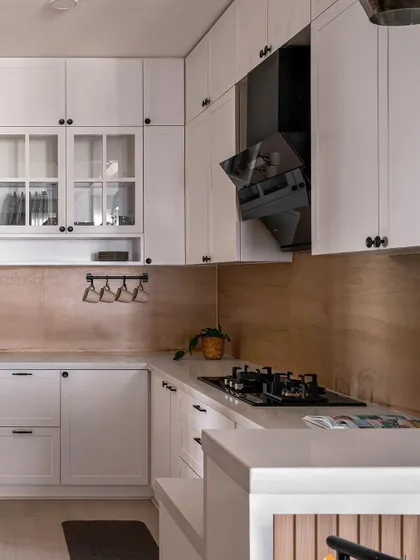 This all-white kitchen is clean, bright, and timeless. We used a wood-look backsplash to add warmth and texture, and included a mix of open and closed storage for both display and practicality.