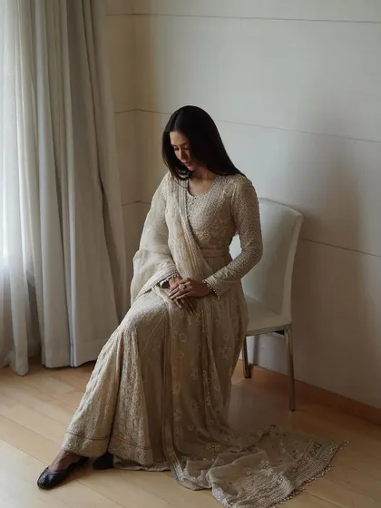 A full-length seated portrait showcasing the beautiful flow and volume of the Tarun Tahiliani anarkali. Paired with traditional juttis, this look is the epitome of regal Indian elegance.