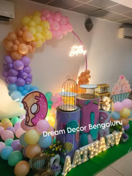 A fun and colorful candy and donut-themed party. The pastel balloon arch and giant donut and cupcake props create a sweet and playful atmosphere.