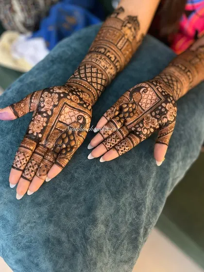I love how the peacock motifs on the palm are complemented by the architectural designs on the wrist in this full-hand mehndi.