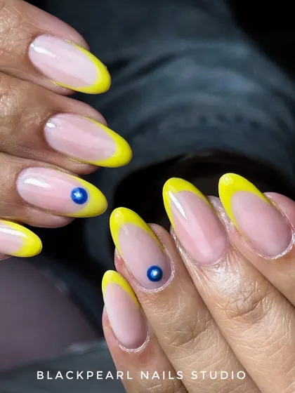 A playful and trendy design featuring bright yellow French tips with an evil eye accent. This look combines a classic technique with a modern, symbolic art piece for a fun and protective vibe.