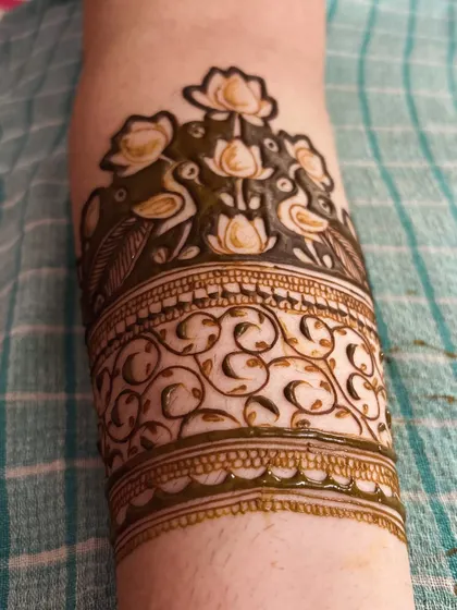 This cuff design for the arm features a beautiful arrangement of lotus flowers and peacocks, creating an elegant and traditional band.